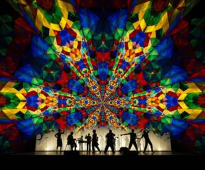 kaleidoscope of colour and shapes above a stage full of performers